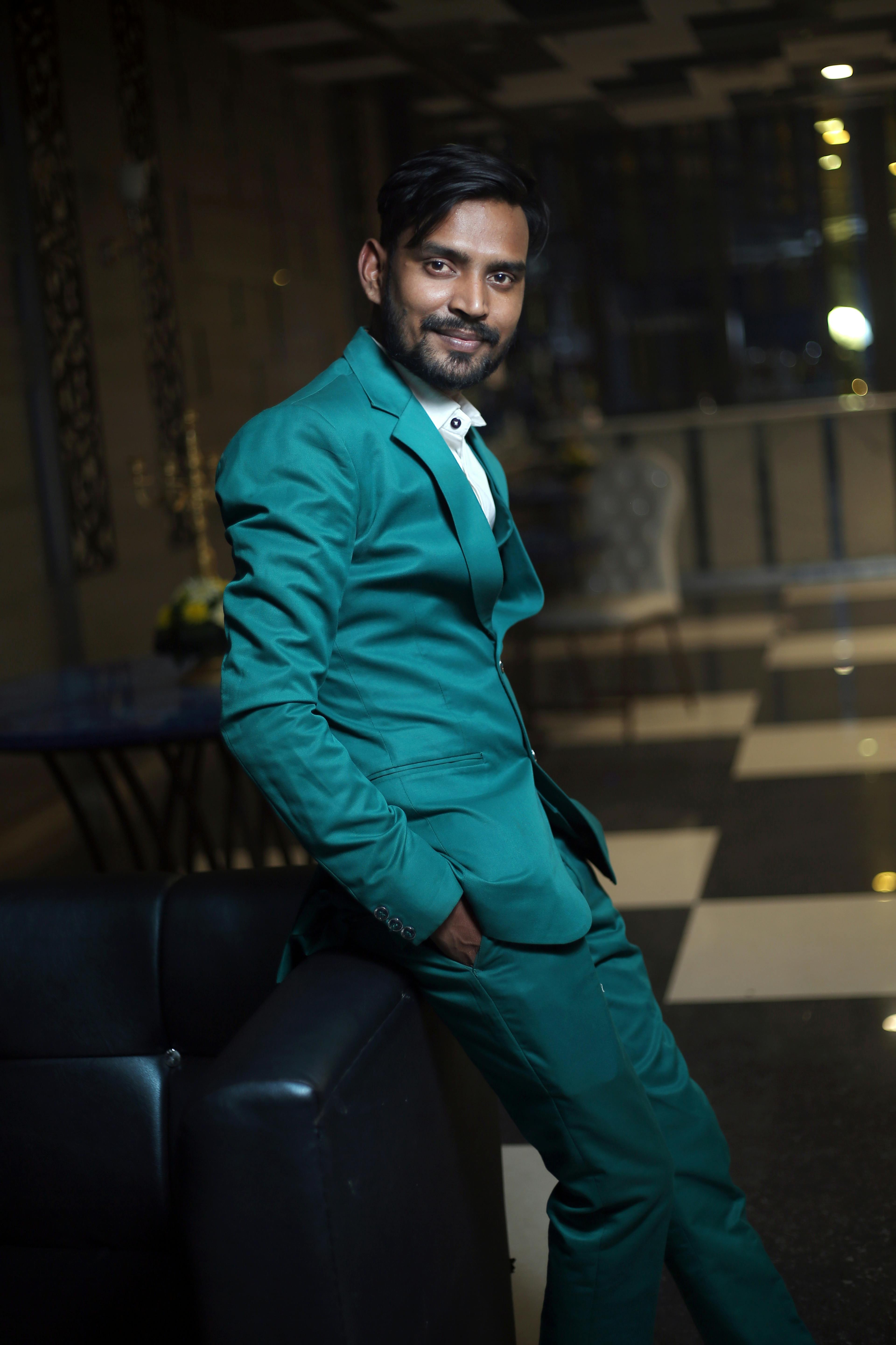 Side view of Indian male in trendy outfit standing in restaurant with hand in pockets and looking at camera
