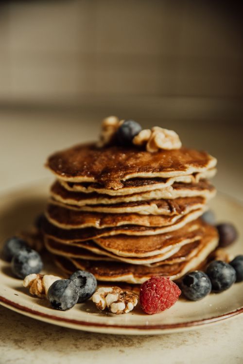 Free A stack of pancakes topped with fresh berries and walnuts, perfect for a healthy breakfast. Stock Photo