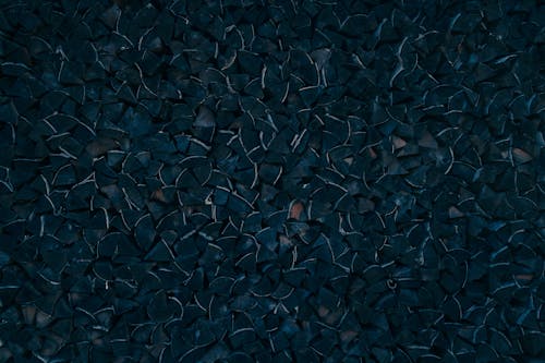 Abstract textured background of dark green triangle shaped pieces forming uneven surface in studio