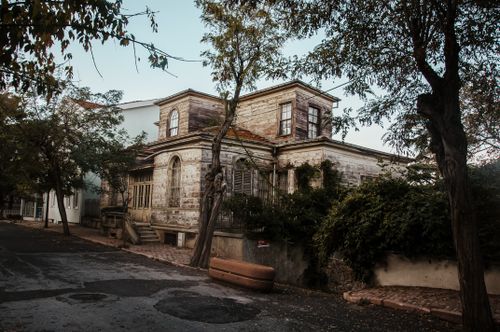 Free Aged stone house exterior against trees and rough roadway under light sky in town Stock Photo