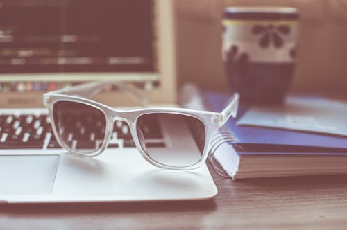 Kostenlos Klare Gerahmte Sonnenbrille Auf Grauem Laptop Stock-Foto