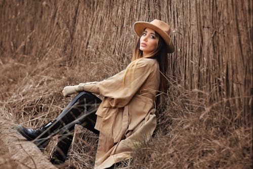 Free Stylish woman sitting on dry grass in nature Stock Photo