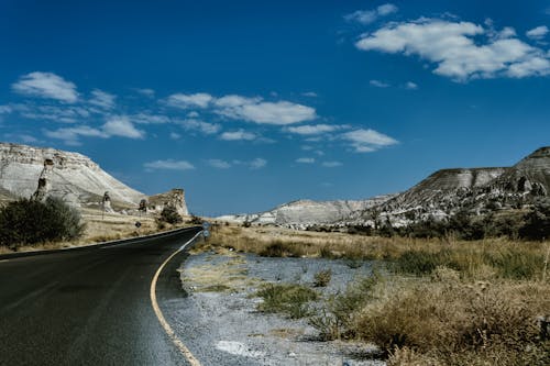 Gray Asphalt Road Between Green Grass Field Under Blue Sky