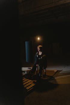 A contemplative person sits alone in a dimly lit interior, creating a moody atmosphere.
