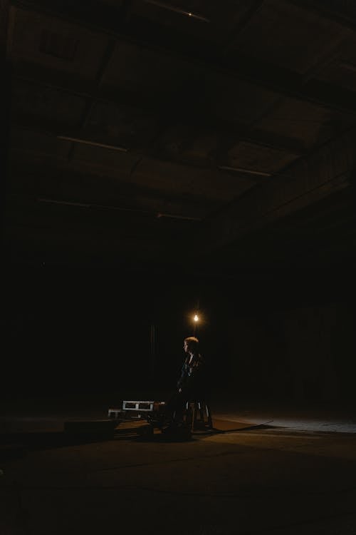 A Person Sitting on the Chair Inside the Dark Warehouse