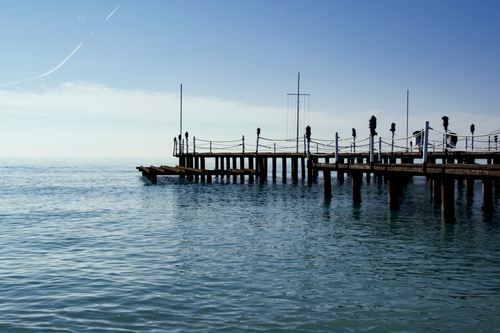 Free A wooden dock extends into the tranquil sea under a clear blue sky. Stock Photo