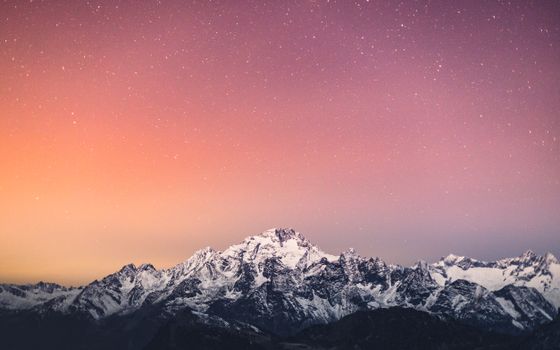 Beautiful snow-covered mountains under a starry sky at twilight in Lanzada, Lombardy.