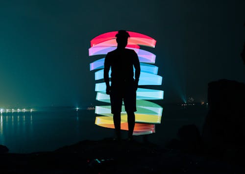 Faceless man near neon illumination on dark seaside