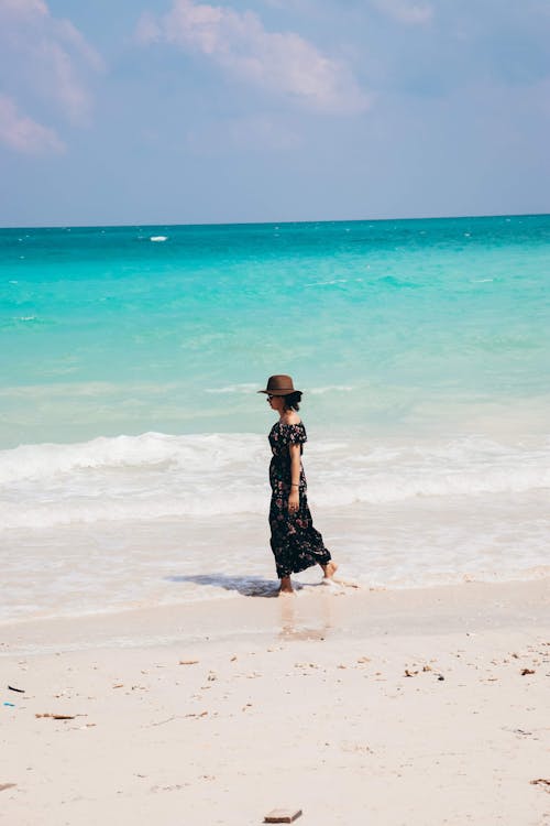 Anonymous woman walking on sandy beach