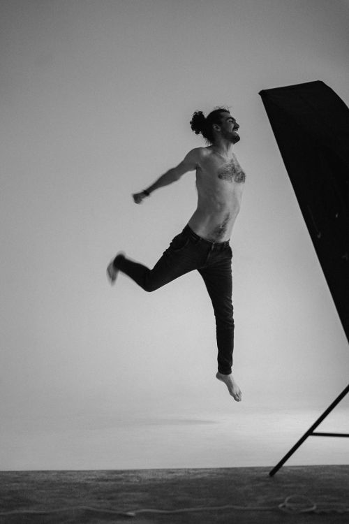Free Captivating shot of a shirtless man jumping midair in a studio setting. Stock Photo