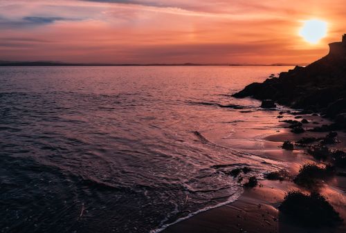 Free Beautiful sunset over the North Sea from Kinghorn Beach, Scotland with bright orange skies and calm waters. Stock Photo