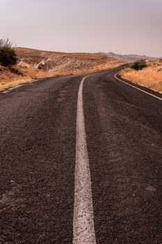A solitary road winding through Turkey's serene mountain landscape, perfect for travel enthusiasts.