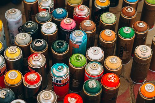 Free Collection of colorful spray paint cans on a concrete surface, ready for creative urban art projects. Stock Photo