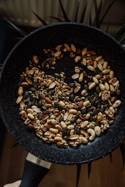 A variety of nuts roasting in a frying pan for a vegan recipe.