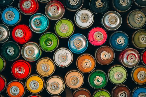 Free Overhead view of vibrant spray paint cans arranged in a flat lay, showcasing a spectrum of colors. Stock Photo