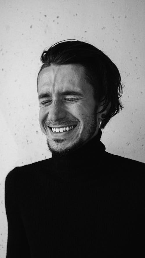Grayscale Photo of a Man in Turtleneck Sleeves Laughing