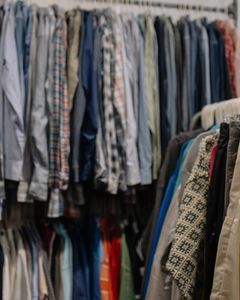 Assorted clothing on racks in a thrift shop, showcasing various styles and colors.