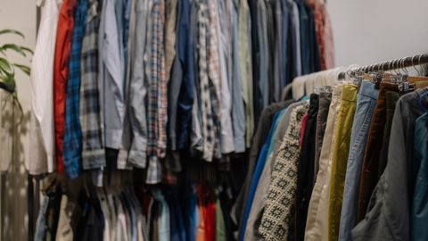 Assorted clothing on racks in a thrift shop, showcasing various styles and colors.
