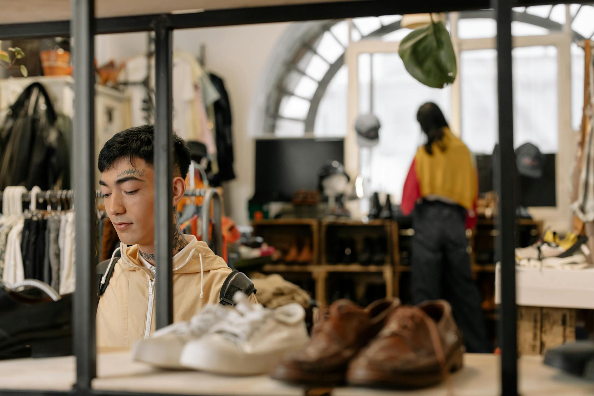 Young adults shopping in a stylish thrift store with varied clothing and shoes.