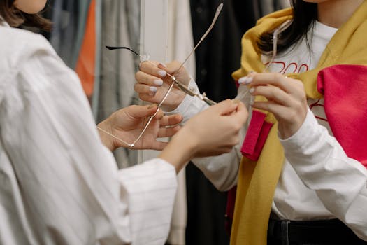 Two women trying on sunglasses in a stylish fashion boutique. Focus on hands and eyewear.