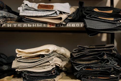 Free Folded jeans neatly stacked on shelves in a retail store, showcasing various styles and sizes. Stock Photo