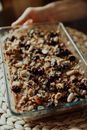 Crop person with granola in baking dish at home