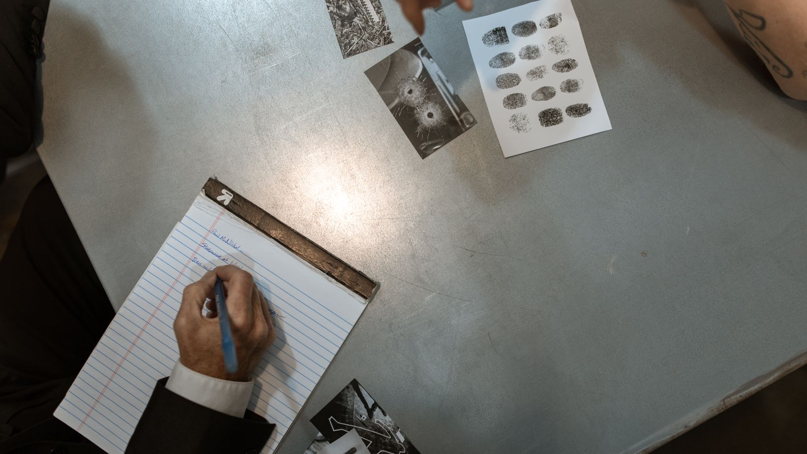 Officers at work reviewing evidence and taking notes in an investigation setting.
