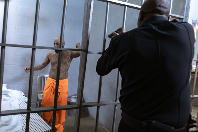 A Law Enforcer Pointing A Gun At A Prisoner