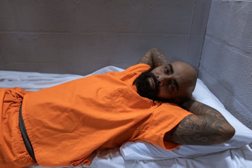 Man in Orange Polo Shirt Lying on Bed