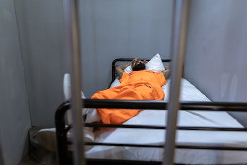 Free Man in Orange Shirt and Pants Lying on Bed Stock Photo