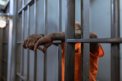 бесплатная Человек в оранжевой рубашке держится на коричневом деревянном заборе Стоковое фото