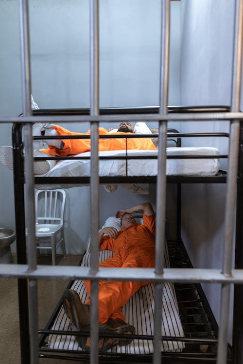 бесплатная Мужчина в оранжевой куртке, лежа на кровати Стоковое фото