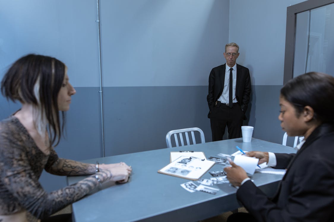 Free A tense scene in a police interrogation room with officers and a suspect discussing evidence. Stock Photo