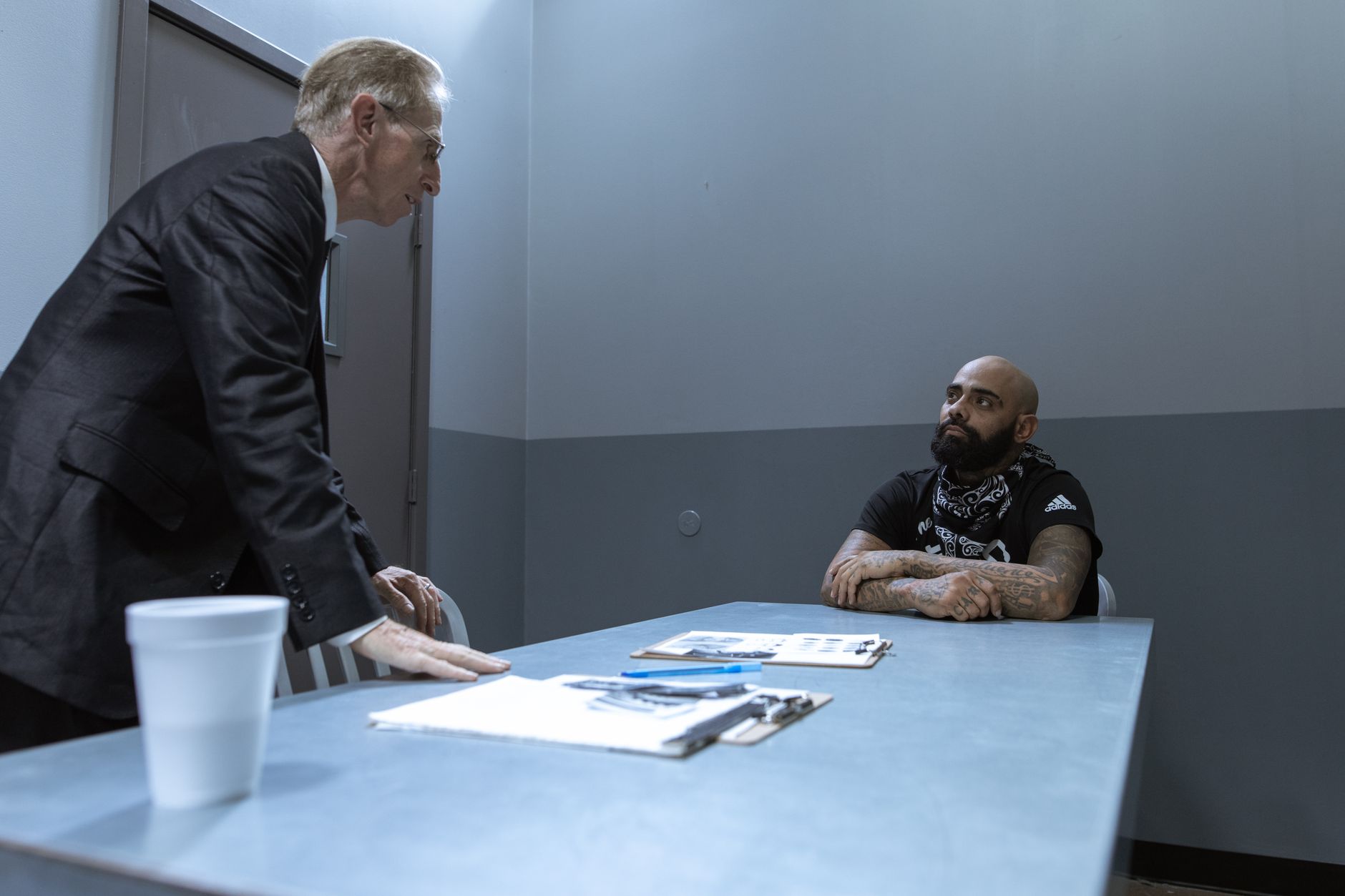 Intense scene in an interrogation room with detective questioning a suspect at a table.