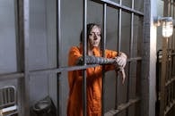 A Woman in Orange Clothes Holding the Metal Bars