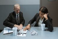Man in Black Suit Jacket Sitting Beside Woman in Gray Long Sleeve Shirt