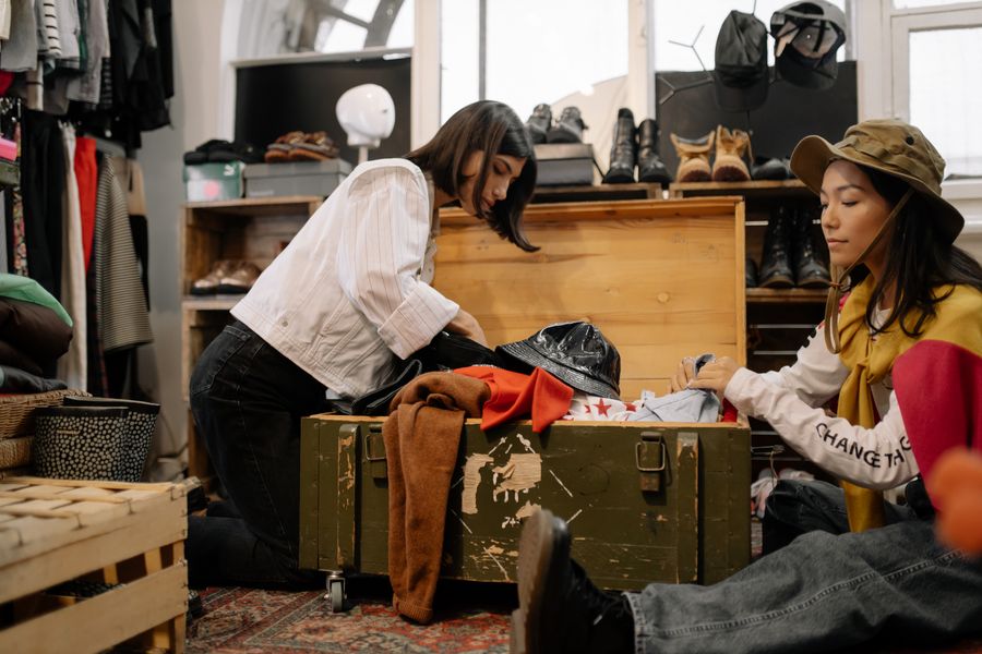 Two people sorting through secondhand clothing in a thrift store