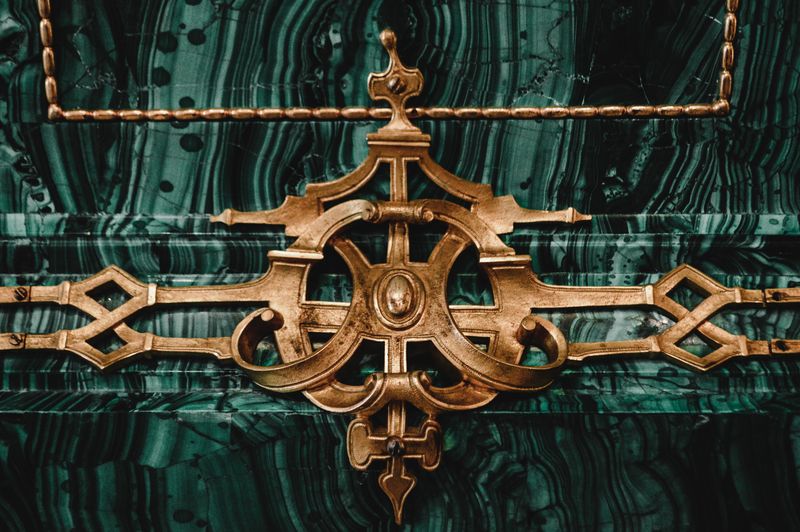 Close-up of intricate gold ornamental design on rich green malachite texture