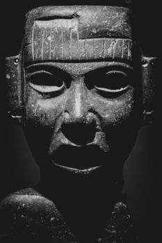 Mysterious stone sculpture with an eerie expression in black and white.