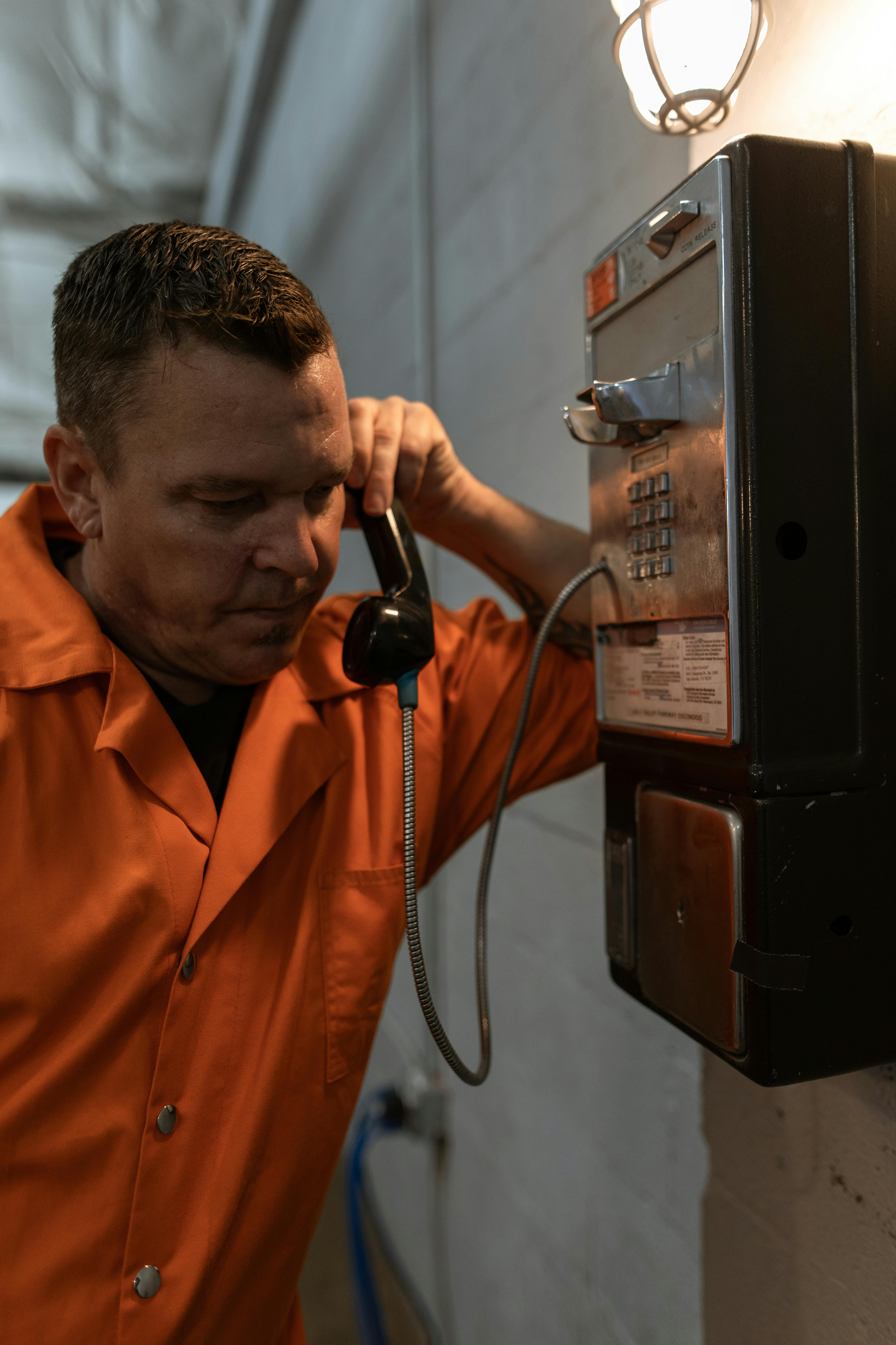 man in orange button up shirt holding telephone