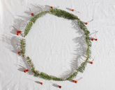 Top view of fresh coniferous branches with red holly berries placed in round on white fabric