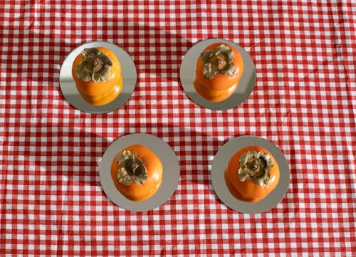 成熟的明亮橙色柿子放在方格桌布的盤子上