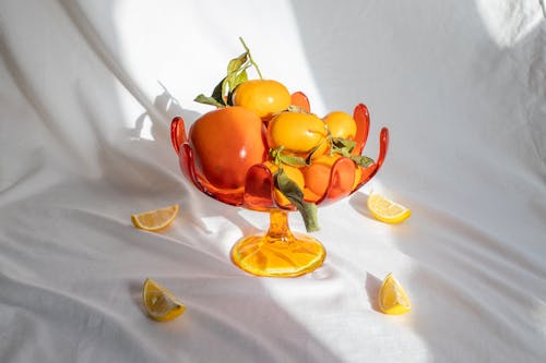 Ripe fruits and persimmon in unusual glass vase
