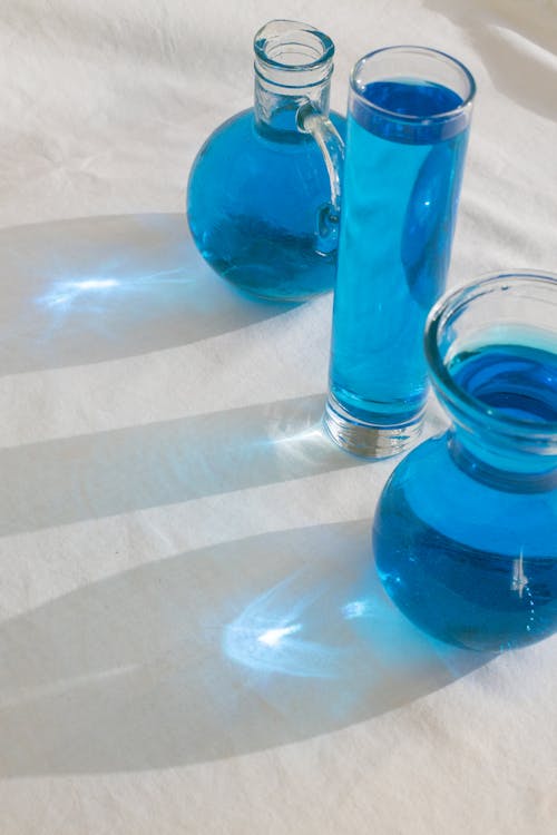 From above of glass bottles with blue clean transparent fluid placed on white surface