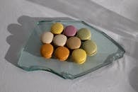 From above of broken piece of glass on white fabric with arrangement of delicious macaroons on top