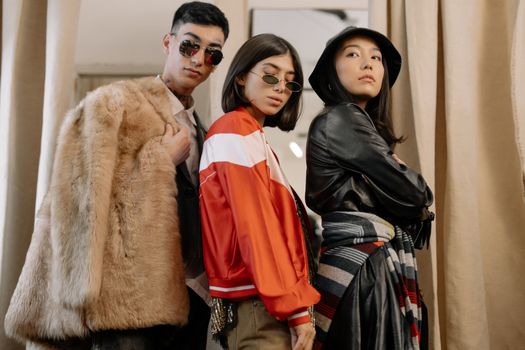 Three adults in fashionable attire posing confidently, reflecting retro and vintage styles.