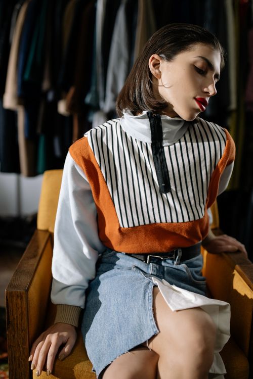 Free A fashionable woman in vintage attire poses elegantly on a chair indoors. Stock Photo