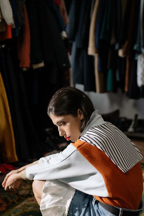 Free Woman posing thoughtfully in a stylish vintage outfit with clothes in the background. Stock Photo