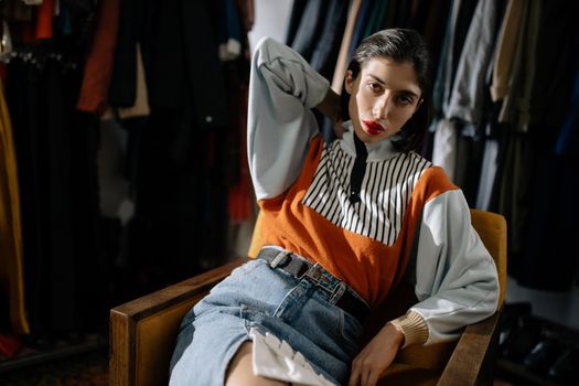 A stylish woman in retro fashion poses in a cozy indoor setting.