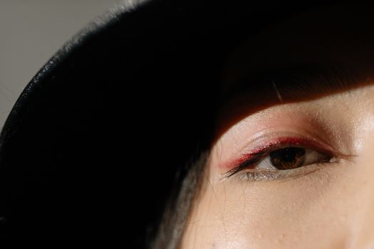 Artistic close-up of an eye with dramatic shadow and minimalistic lighting, creating an intense visual effect.